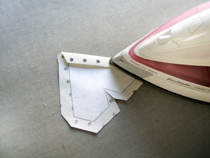 Planchar los excesos de tejido hacia el interior de la pieza Recortar los márgenes de costura para doblar hacia dentro Adherir con plancha el patrón de freezer paper en la parte de atrás del tejido | Betsy Costura